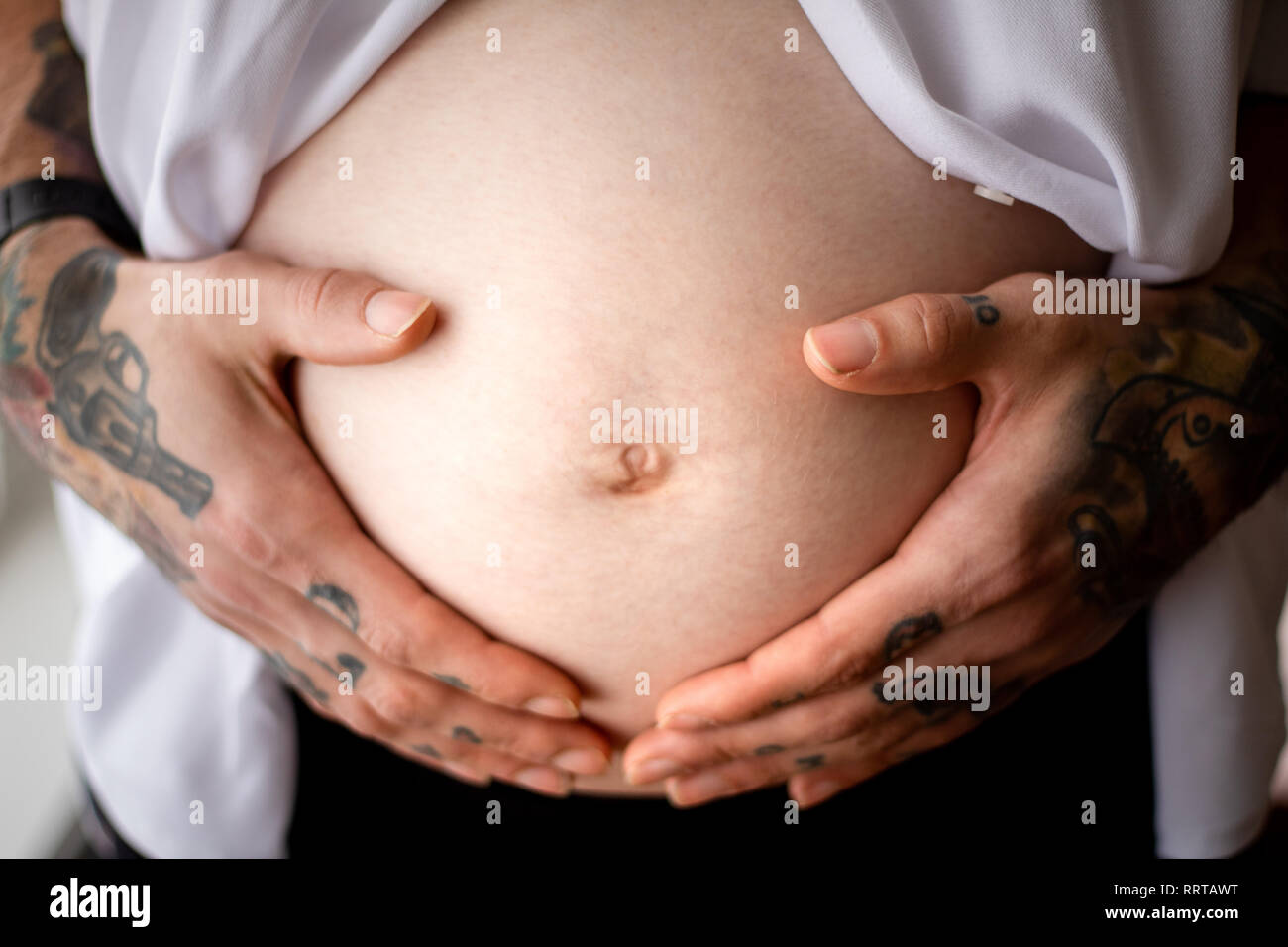 Dad tätowierte Hände Wiege ihren schwangeren Bauch Stockfoto