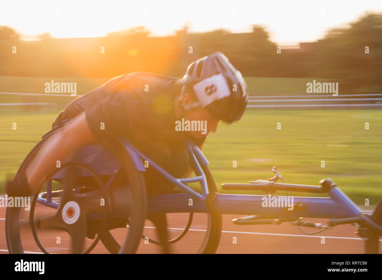 Entschlossene junge weibliche paraplegic Athlet Beschleunigung zusammen Sport Track im Rollstuhl Rennen Stockfoto