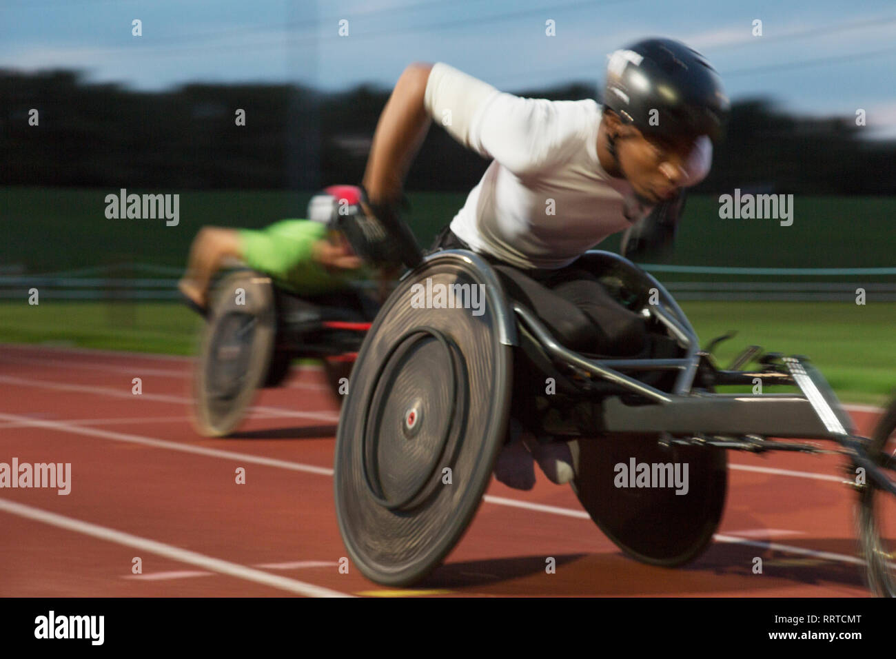 Bestimmt jungen männlichen querschnittsgelähmten Athlet Beschleunigung zusammen Sport Track im Rollstuhl Rennen Stockfoto