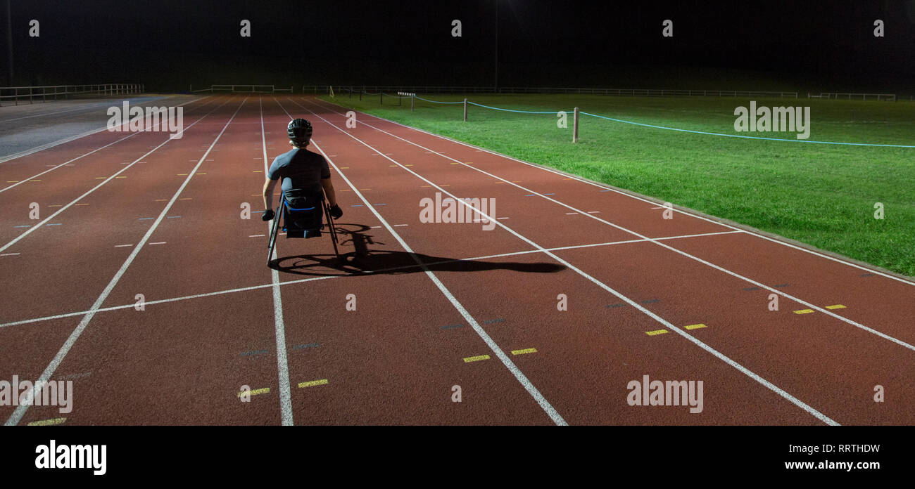 Paraplegic Athlet Training für Rollstuhl Rennen am Sportplatz in der Nacht Stockfoto