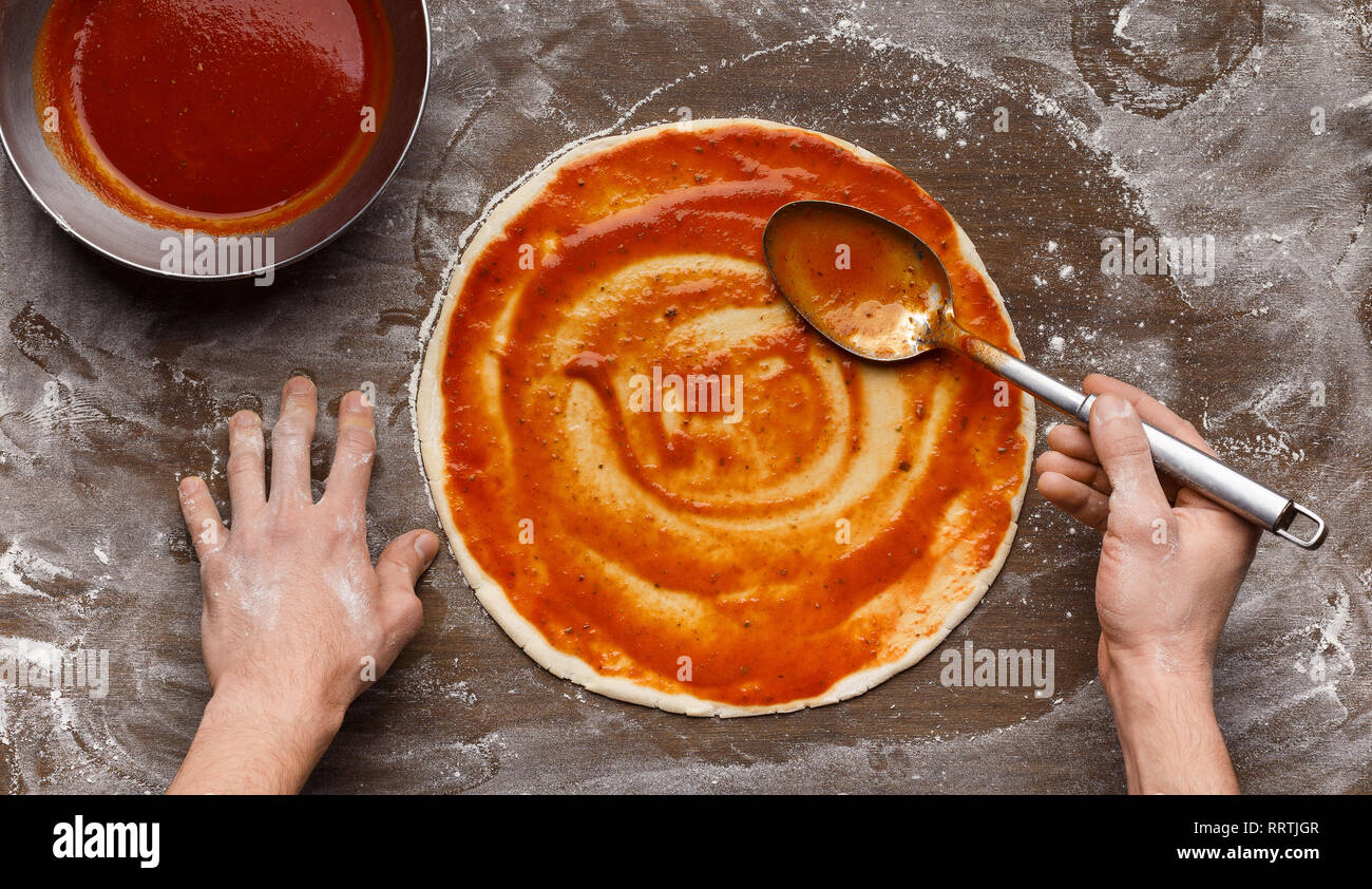 Mann hinzufügen Tomatensauce pizza Base auf Italienisch Stockfoto