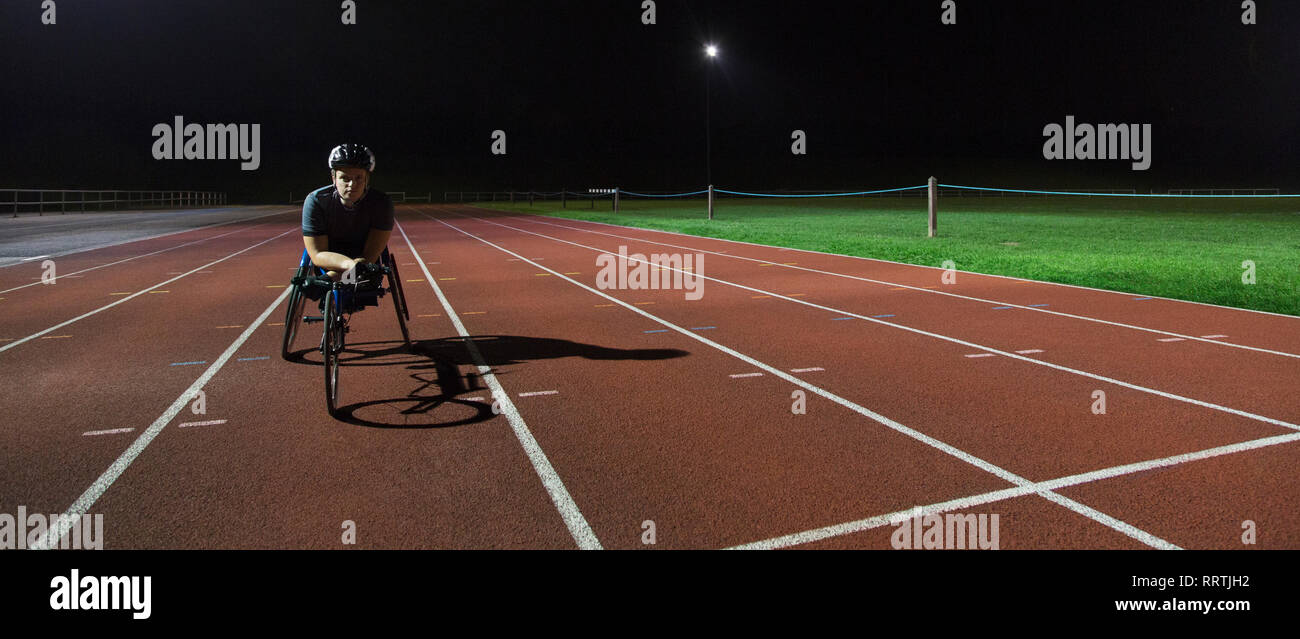 Portrait zuversichtlich , Junge weibliche paraplegic Athlet Training für Rollstuhl Rennen am Sportplatz in der Nacht Stockfoto