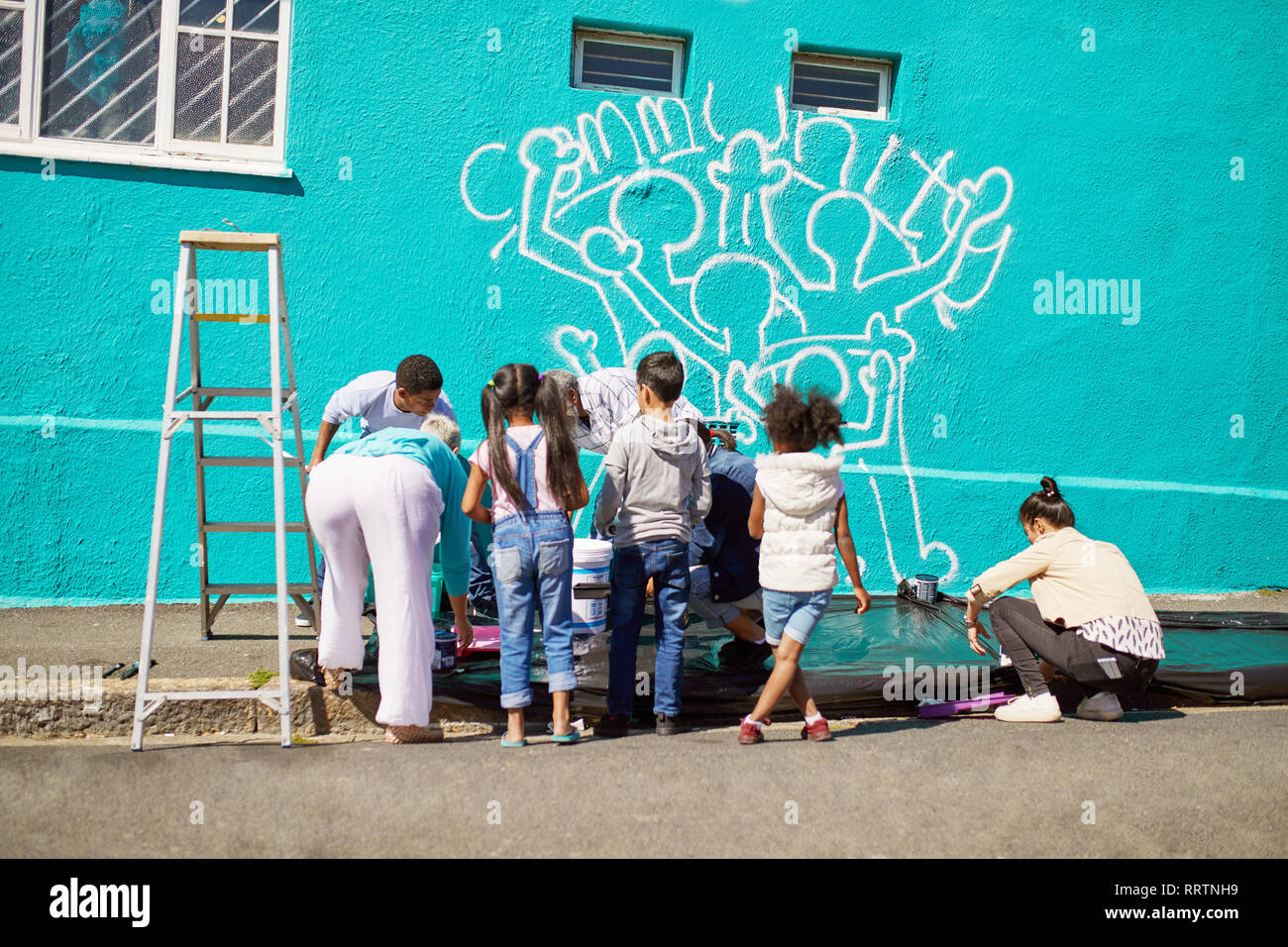 Kid freiwillige Malerei Gemeinschaft Wandbild an sonnigen Wand Stockfoto