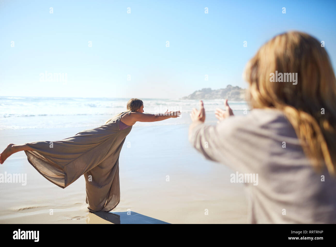 Frau üben Krieger 3 Pose an sonnigen Strand während Yoga Retreat Stockfoto