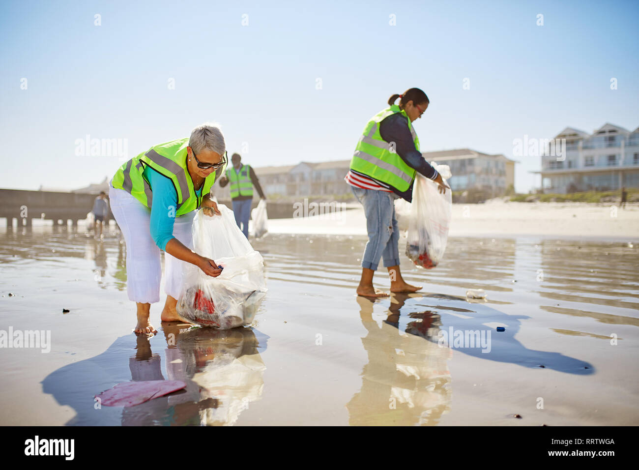 Weibliche freiwillige Aufnehmen Wurf auf sonnigen feuchten Sand Strand Stockfoto