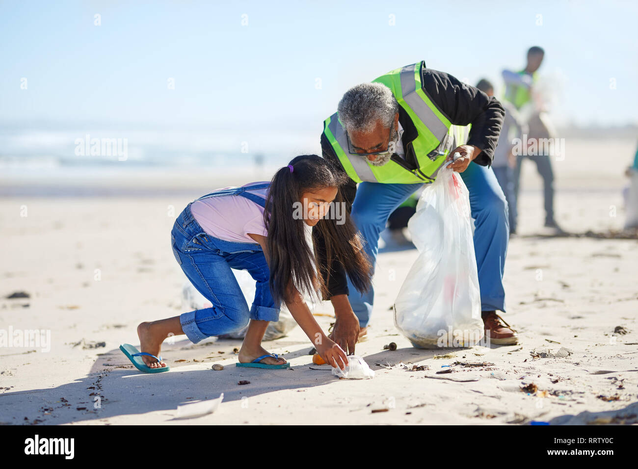 Großvater und Enkelin freiwillige Reinigung Wurf am sonnigen Sandstrand. Stockfoto