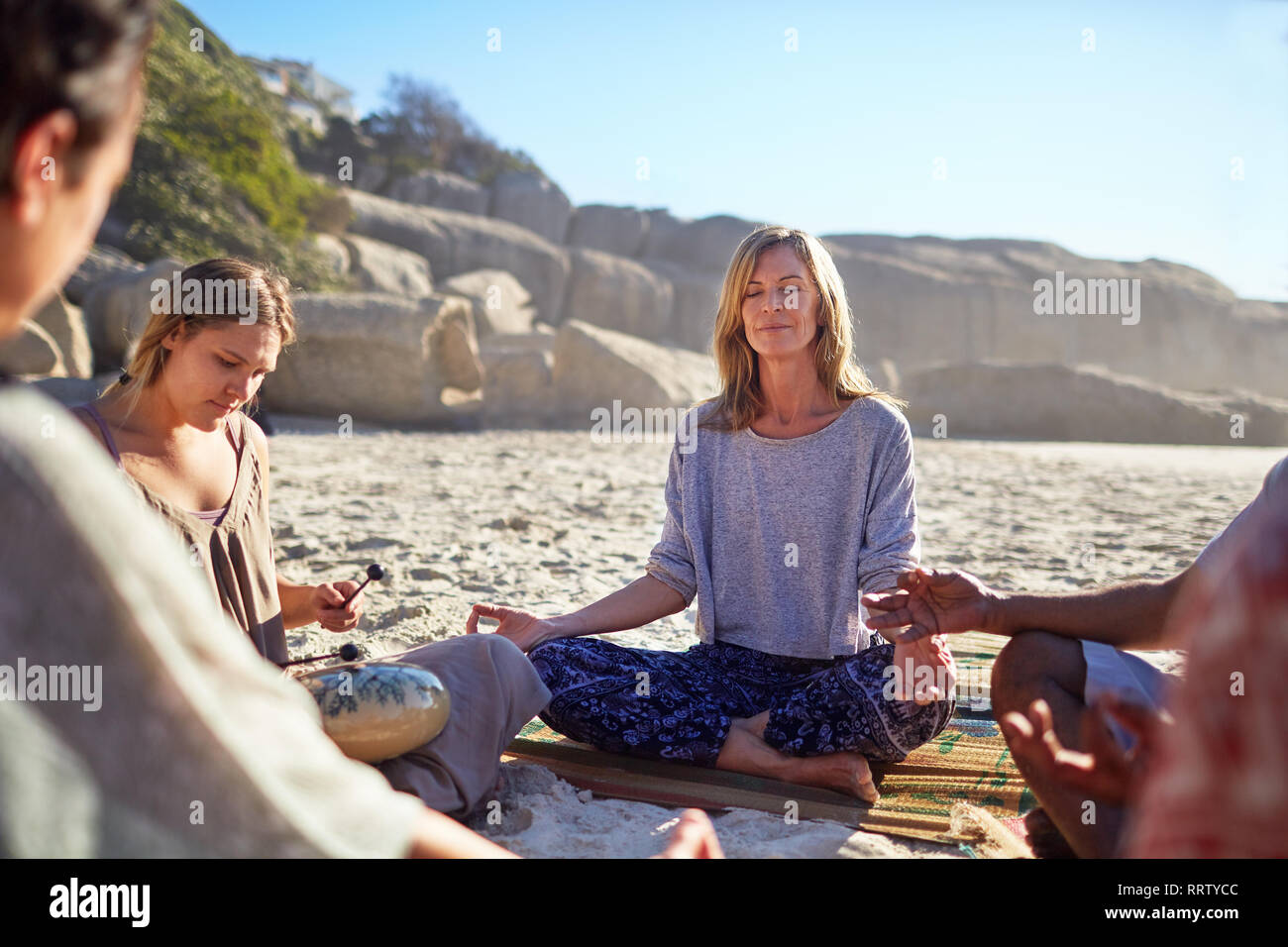 Ruhige Frau, meditieren im Kreis an sonnigen Strand während Yoga Retreat Stockfoto