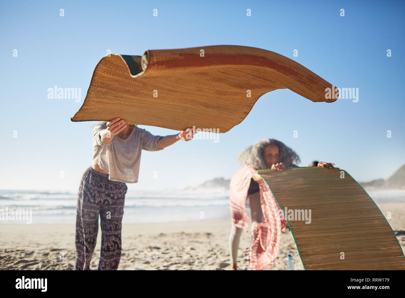 Frau Festlegung Yogamatten an sonnigen Strand während Yoga Retreat Stockfoto