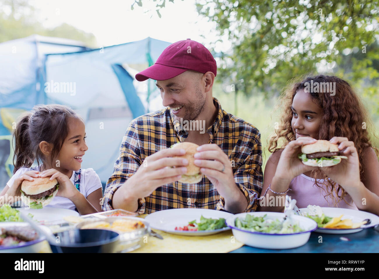 Vater und Tochter genießen Grill Hamburger Mittagessen auf dem Campingplatz Stockfoto