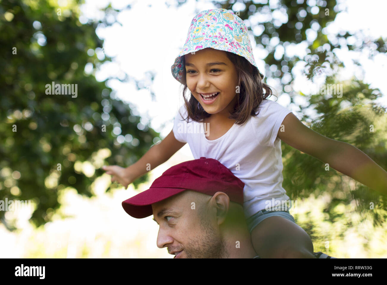 Glückliche, unbeschwerte Mädchen auf des Vaters Schultern Stockfoto