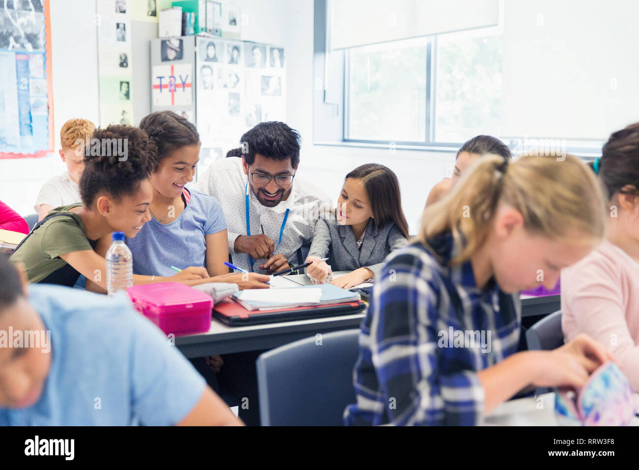 Lehrer helfen Junior high school Kursteilnehmer am Schreibtisch im Klassenzimmer Stockfoto