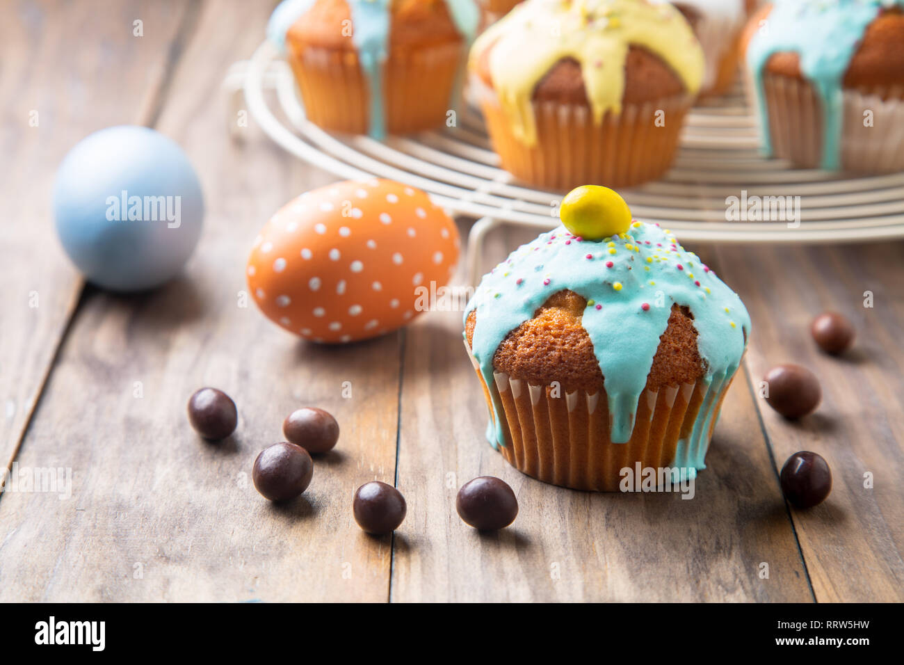 Ostern cupcakes glasiert mit bunten Zucker, besprüht und Schokolade und bemalte Eier auf einem rustikalen Holztisch Stockfoto
