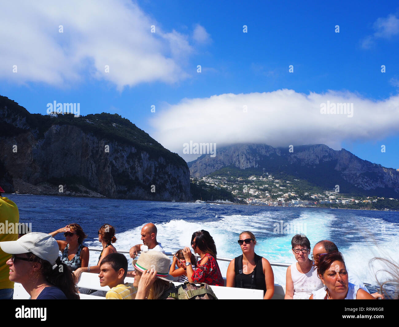 Ein Blick auf Capri als ein Boot voller Touristen macht seine Abfahrt nach einem Tagesausflug von Ischia, Italien Stockfoto