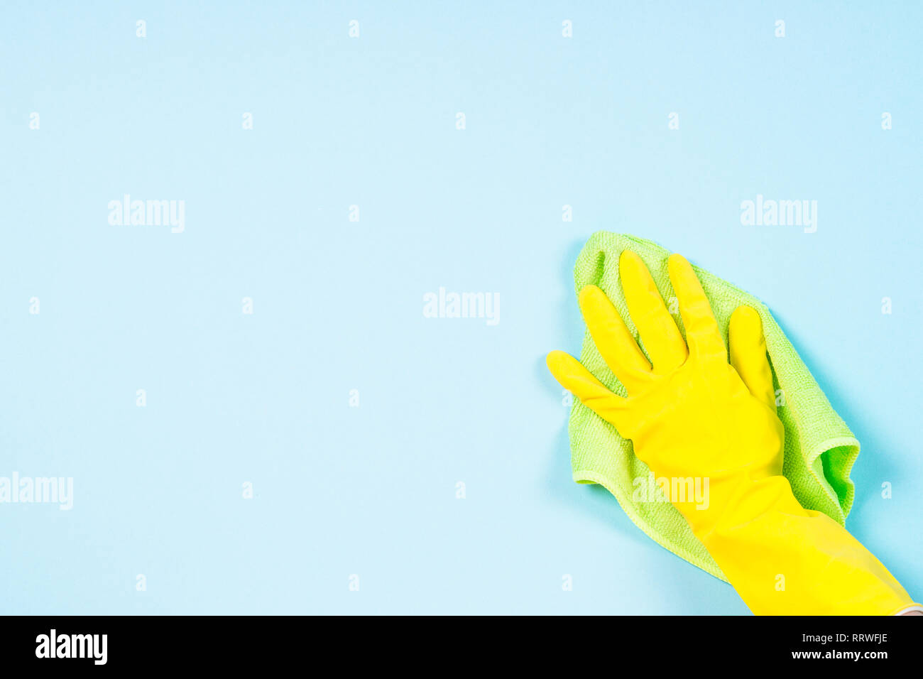 Hand in gelb Handschuhe und Mikrofaser Tuch reinigen blauen Hintergrund. Stockfoto