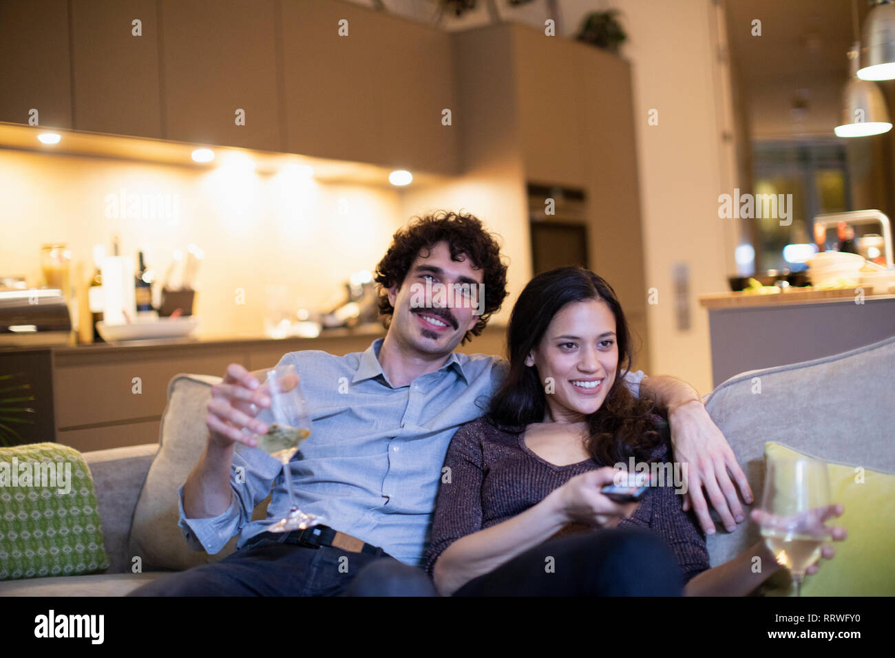 Glückliches Paar Weißwein trinken und fernsehen auf Apartment Sofa Stockfoto
