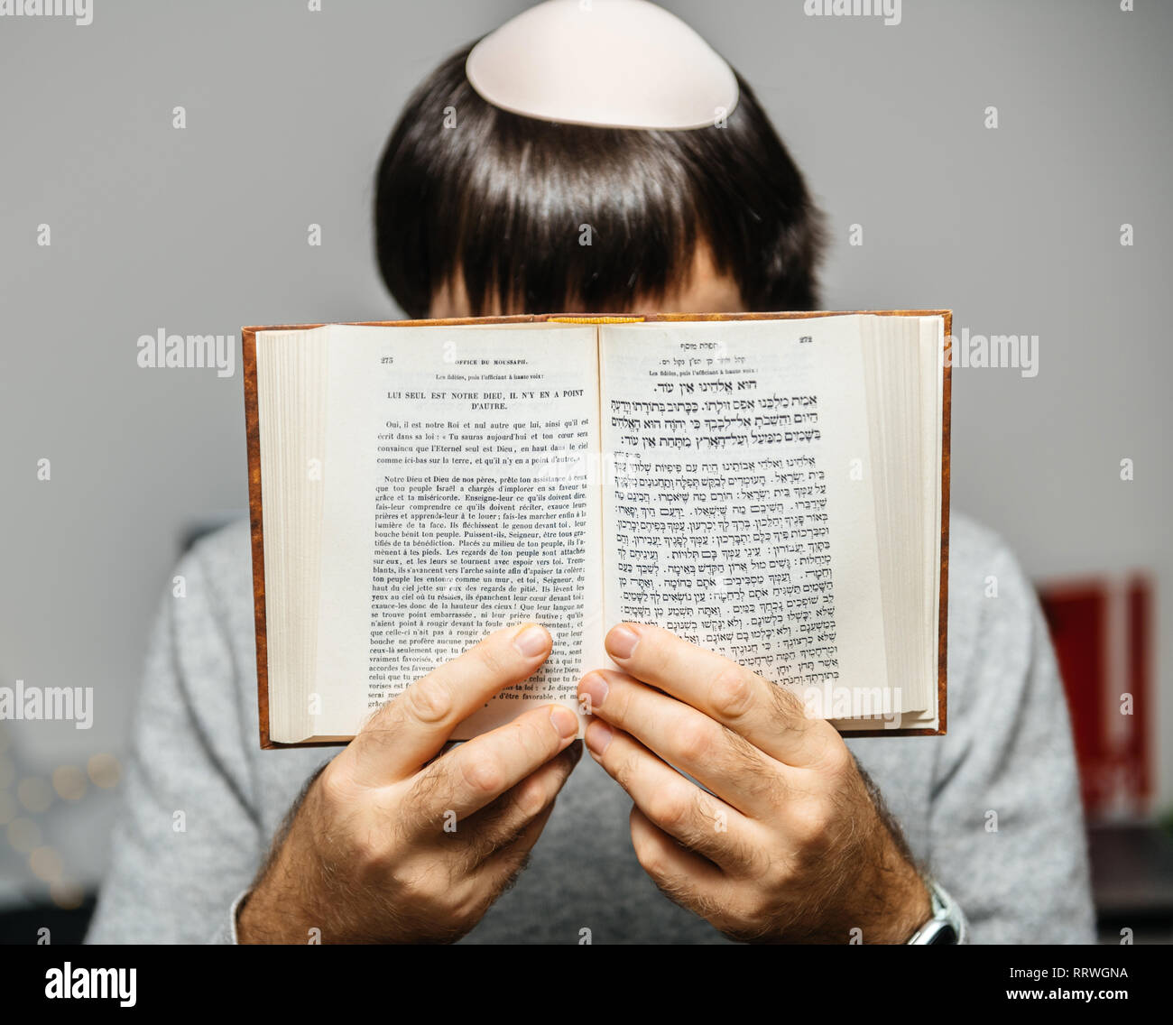 Junge jüdische Männer tragen Kippa betende Lesung Mehrsprachig Hebräisch Französisch machzor Gebetbuch von 1920 auf die Hohen Feiertage Rosch Haschanah und Jom Kippur Text vor. Stockfoto