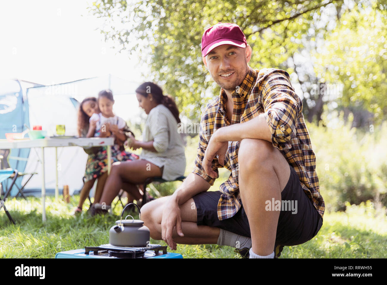 Portrait zuversichtlich Mann Heizung Teekanne auf Campingkocher bei Sunny Campingplatz Stockfoto