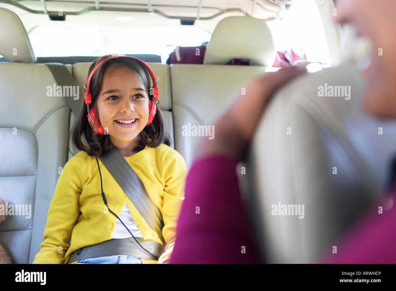 Lächelnde Mädchen mit Kopfhörern Reiten in Rücksitz des Autos Stockfoto