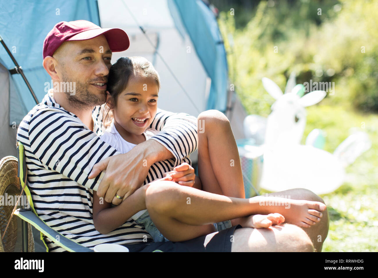 Liebevoller Vater umarmt Tochter bei Sunny Campingplatz Stockfoto