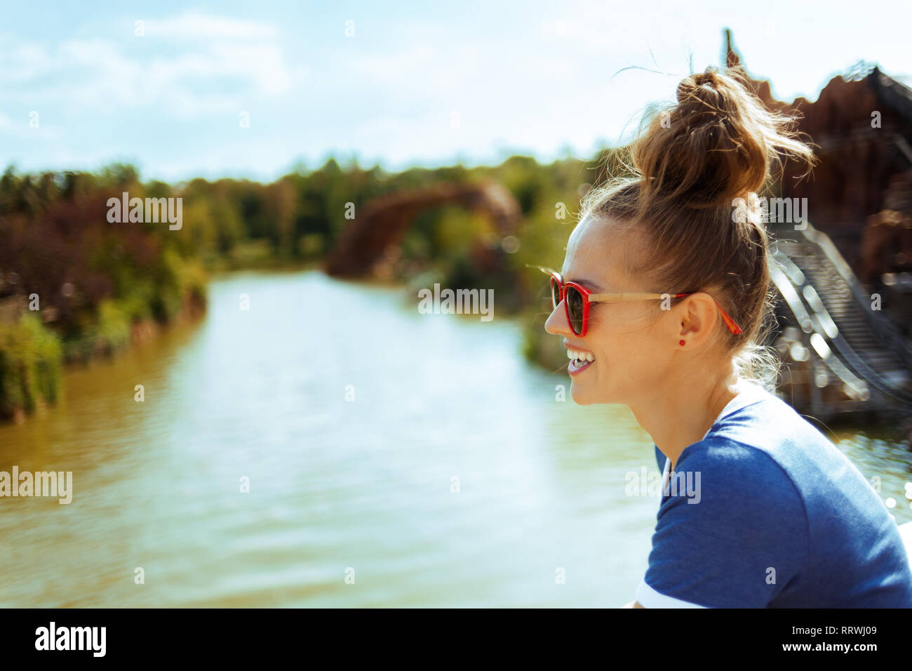 Lächelnd gesunde alleinreisender Frau in Blau t-shirt auf dem Fluss Boot erkunden Sie die Landschaft mit Fluss Kreuzfahrt. Stockfoto