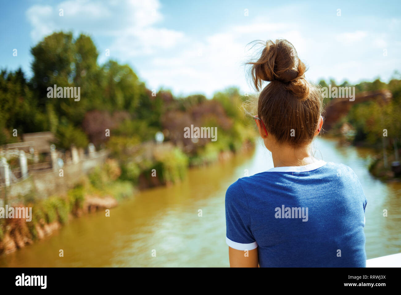 Von hinten gesunde Solo touristische Frau in Blau t-shirt auf dem Fluss Boot erkunden Sie die Landschaft mit Fluss Kreuzfahrt. Stockfoto