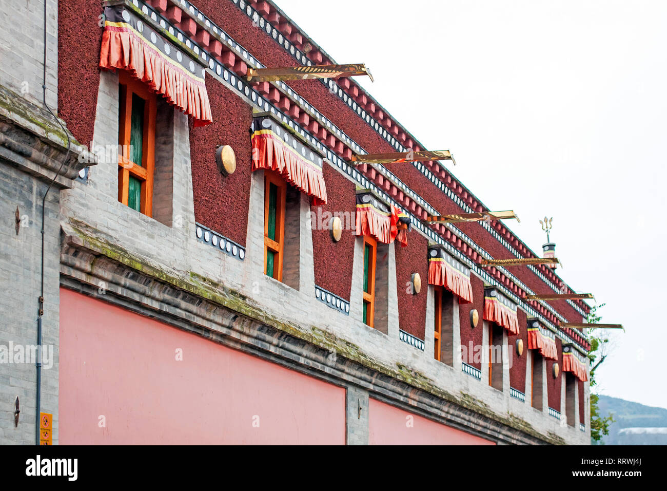 Bunte tibetischer Architektur. Detaillierte Fassade des obersten Etage des Traditionellen buddhistischen Gebäude. Rote chinesische Windows. Stockfoto