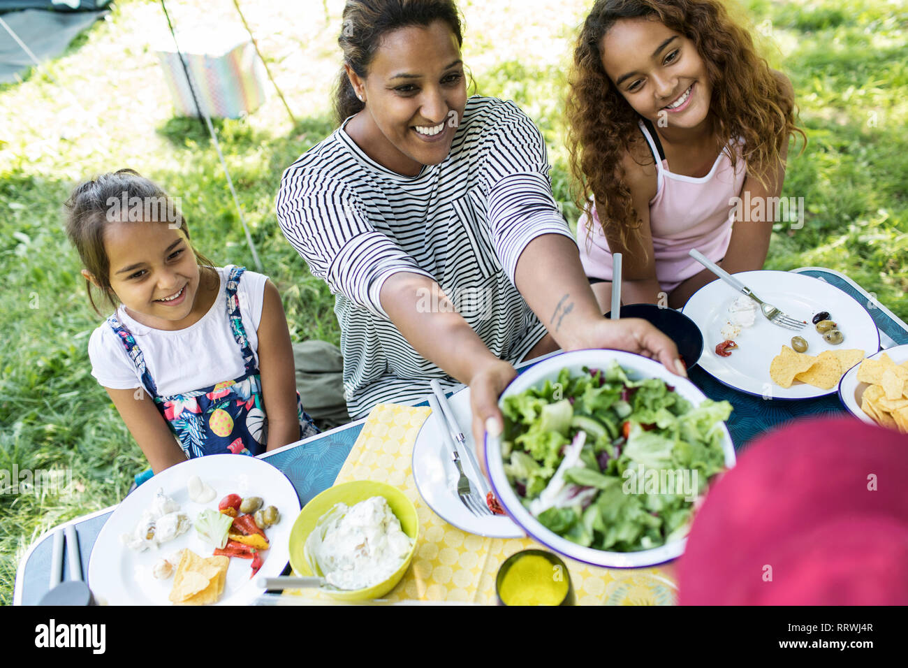 Glückliche Mutter und Töchter genießen Salat Mittagessen auf einem Campingplatz Tabelle Stockfoto