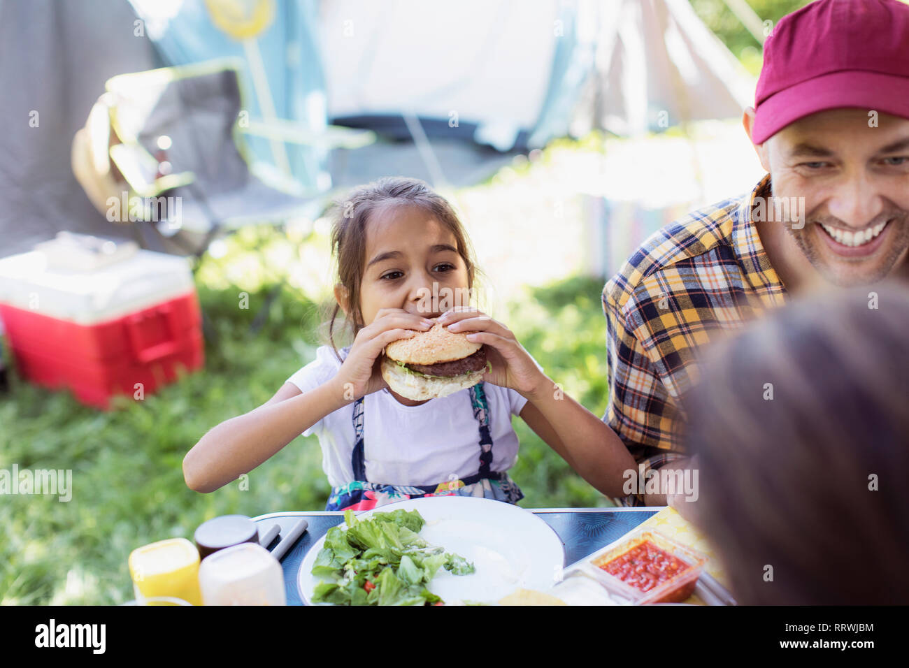Vater und Tochter essen Grill Hamburger auf dem Campingplatz Stockfoto
