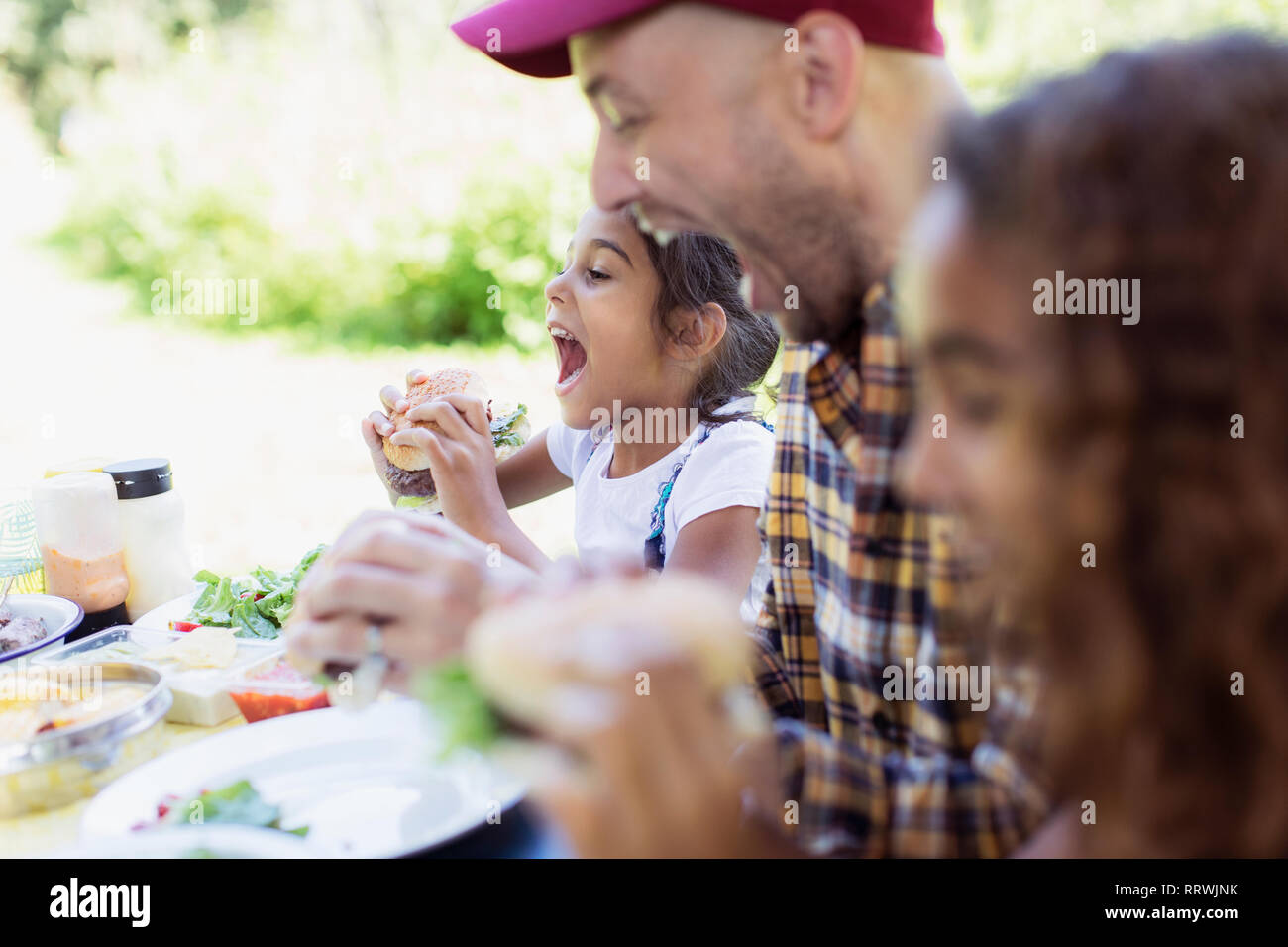 Verspielt Vater und Tochter essen Grill Hamburger auf dem Campingplatz Stockfoto