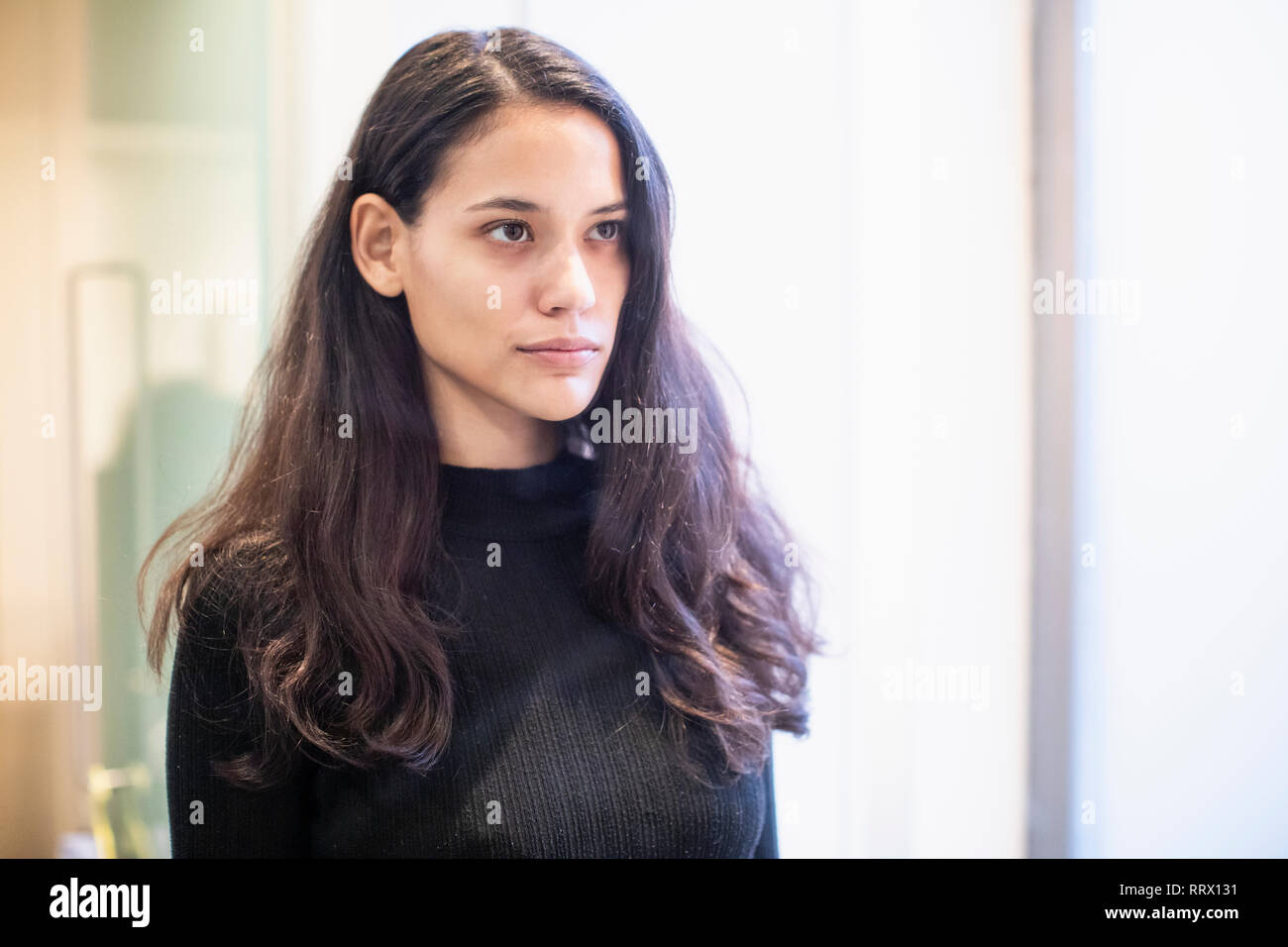 Ernsthafte brünette Frau, die an der Reflexion im Badezimmer Spiegel Stockfoto