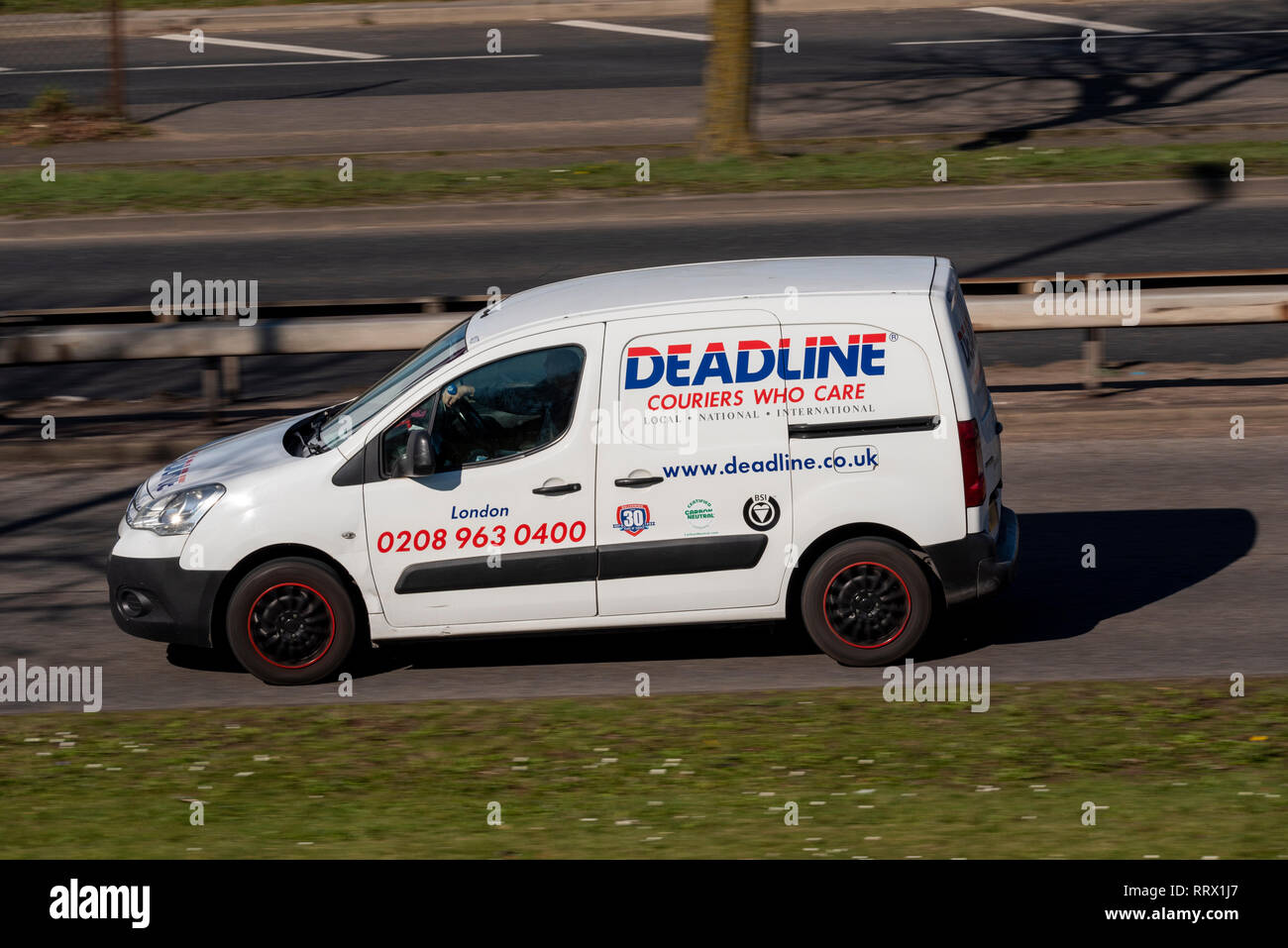 Terminkuriere, die sich kümmern, weißer Van, der auf der Straße fährt. Post, Paketkurierdienst Stockfoto