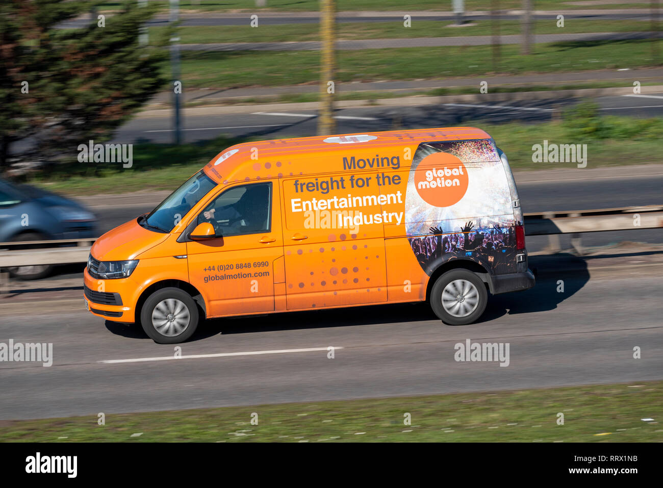 Global Motion Transporter auf der Straße. Transport von Fracht für die Unterhaltungsindustrie. Orangefarbener Van Stockfoto