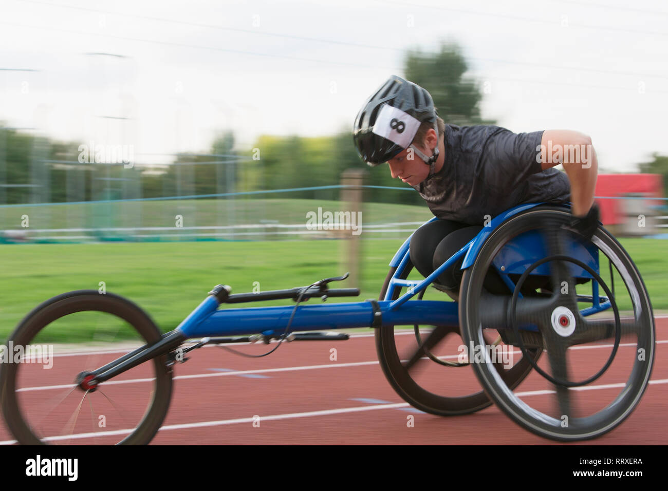 Entschlossene junge weibliche paraplegic Athlet Beschleunigung zusammen Sport Track im Rollstuhl Rennen Stockfoto