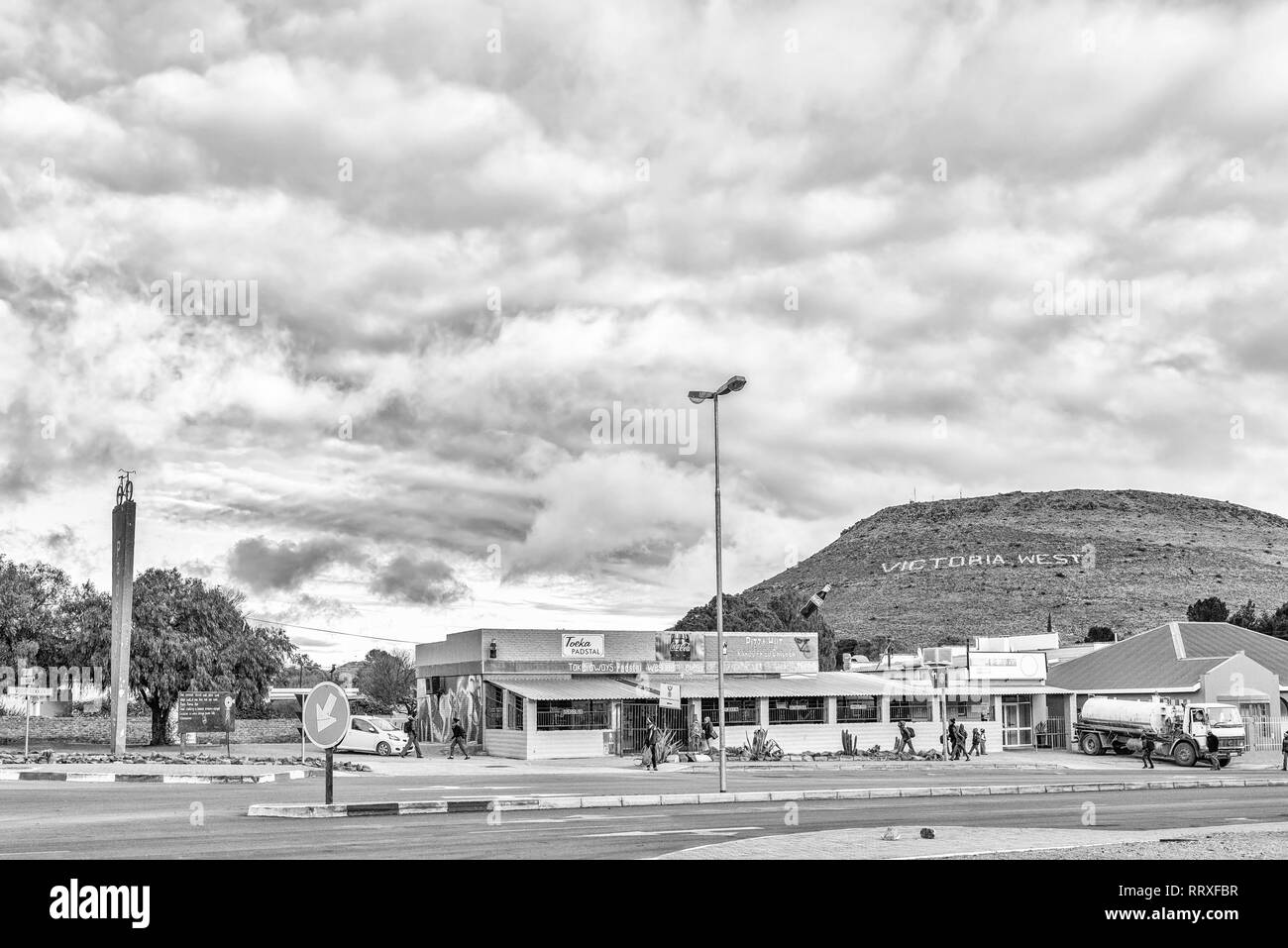 VICTORIA WEST, SÜDAFRIKA, August 7, 2018: ein Sonnenaufgang street scene, mit einer Straße ausgeht, Fahrzeuge und Personen, in Victoria West. Die Stadt name ist visibl Stockfoto