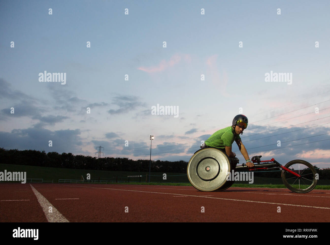 Jungen männlichen querschnittsgelähmten Athlet Training für Rollstuhl Rennen am Sportplatz in der Nacht Stockfoto