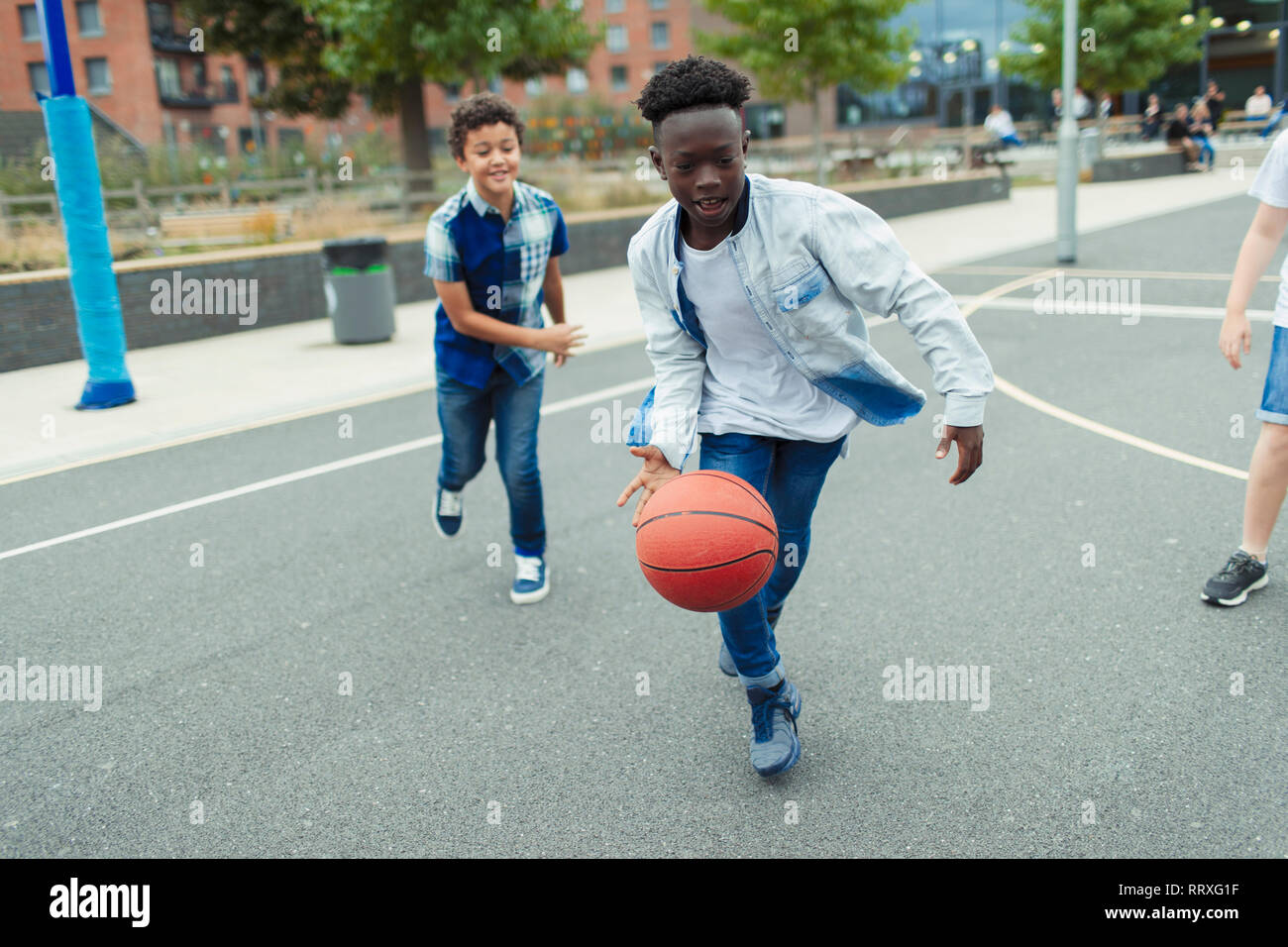 Tween Jungen Basketball spielen im Schulhof Stockfoto