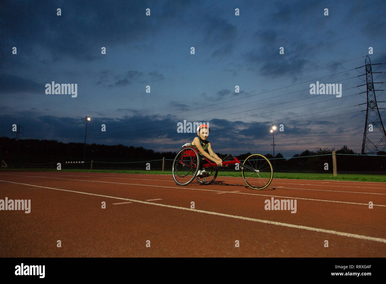 Portrait zuversichtlich Jugendmädchen paraplegic Athlet Training für Rollstuhl Rennen am Sportplatz in der Nacht Stockfoto