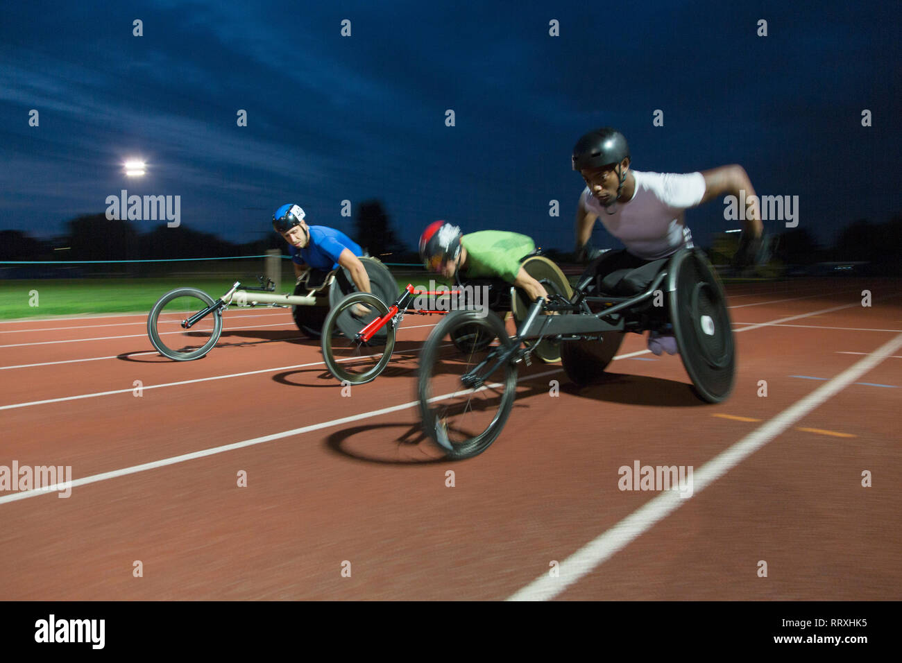 Querschnittsgelähmte Sportler racing zusammen Sport Track im Rollstuhl Rennen in der Nacht Stockfoto