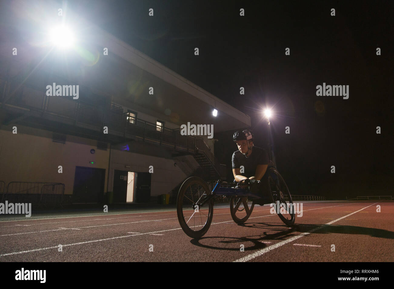 Bestimmt weiblichen paraplegic Athlet Training für Rollstuhl Rennen am Sportplatz in der Nacht Stockfoto