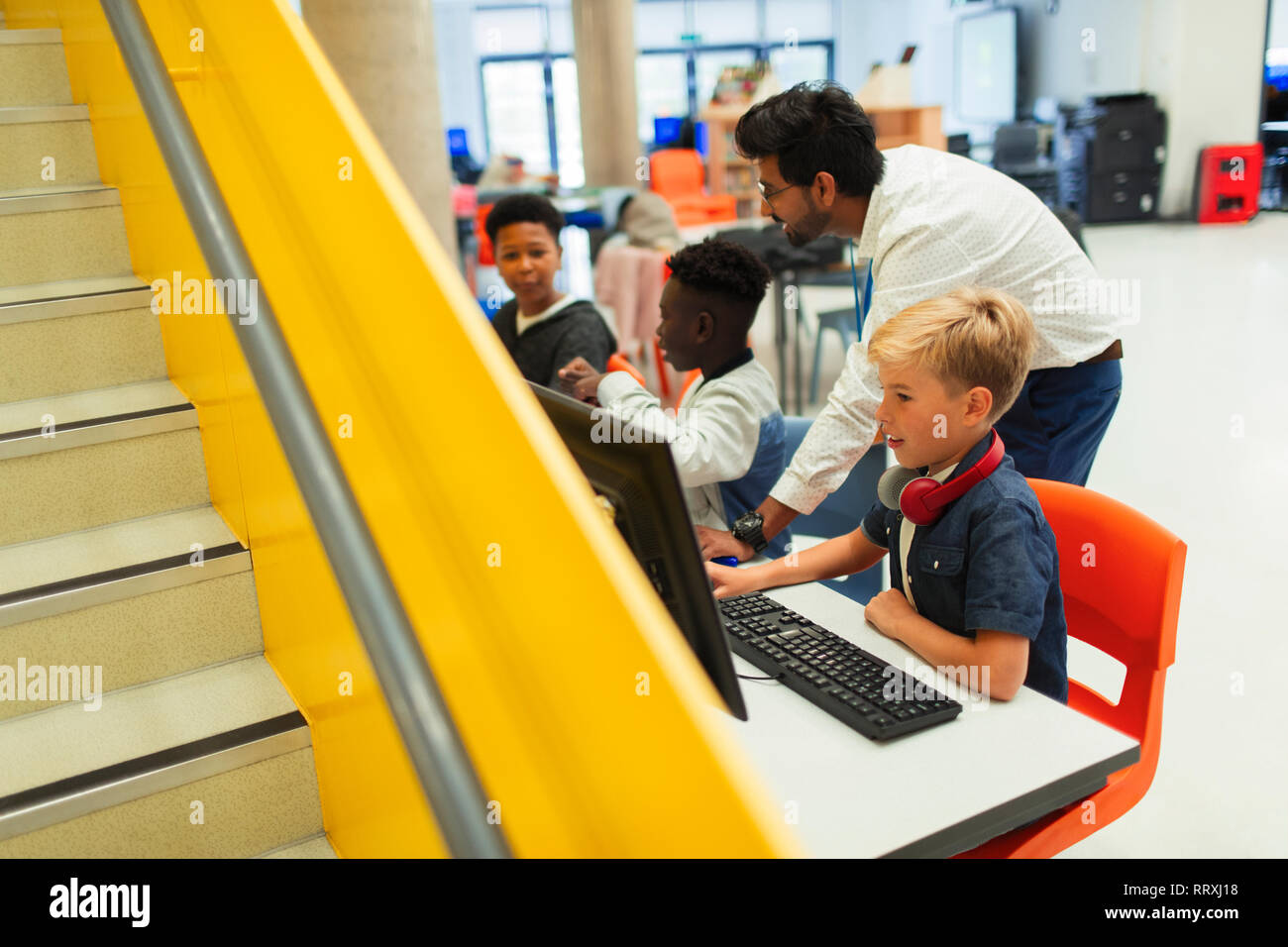 Lehrer helfen Junior high Schüler mit Computern in der Bibliothek Stockfoto