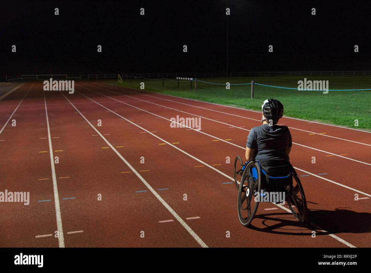 Bestimmt weiblichen paraplegic Athlet Training für Rollstuhl Rennen am Sportplatz in der Nacht Stockfoto
