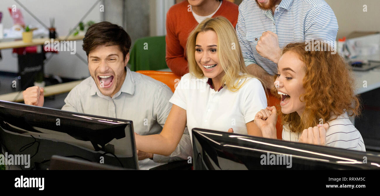 Aufgeregt Studenten lesen gute Nachrichten zusammen auf Bildschirm Stockfoto