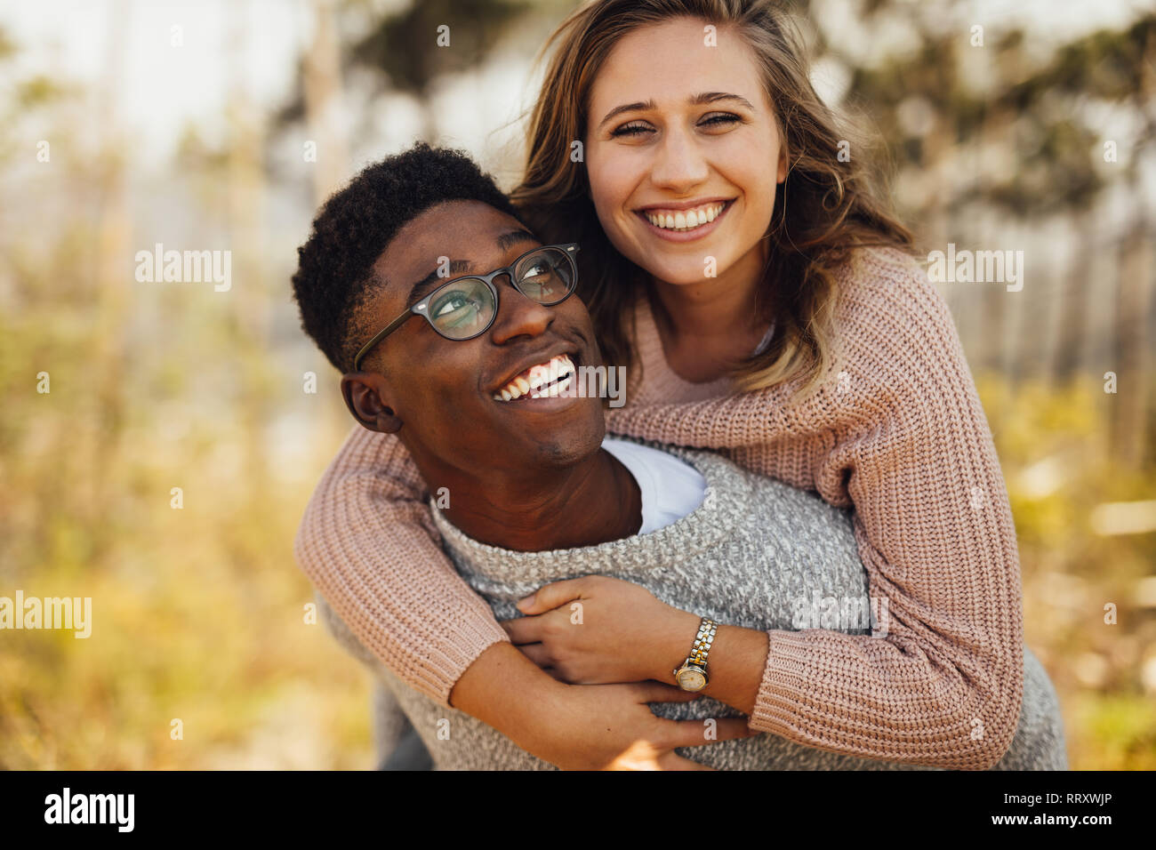 Junge afrikanische Mann huckepack seine Freundin. Interracial Paare Spaß im Freien. Stockfoto