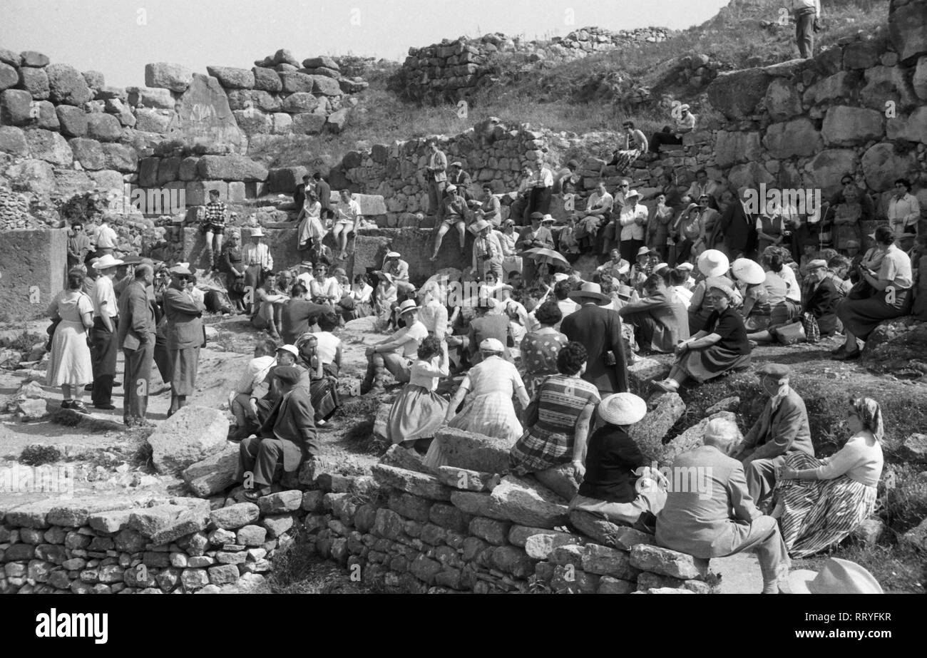 Spanien, Griechenland - Gebannt hört sich eine Touristengruppe sterben Ausführungen Ihres Reiseleiters bei den archäologischen Stätten von Mykene, Panorama, 1950er Jahre. Eine interessierte Gruppe von Touristen hören zu den Erklärungen ihrer Tour Guide in Mykene in Griechenland, 1950. Stockfoto