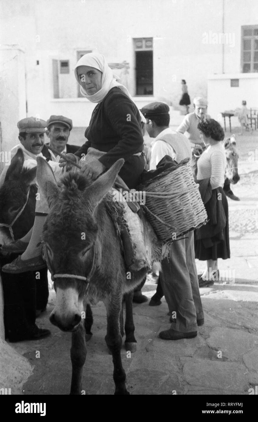 Spanien, Griechenland - Eine Frau reitet mit ihrem Esel durch eine Gasse in einem Dorf in Spanien, 1950er Jahre. Eine Frau, die auf dem Esel ritt und thtrough die Gassen von einem Dorf in Griechenland, 1950. Stockfoto