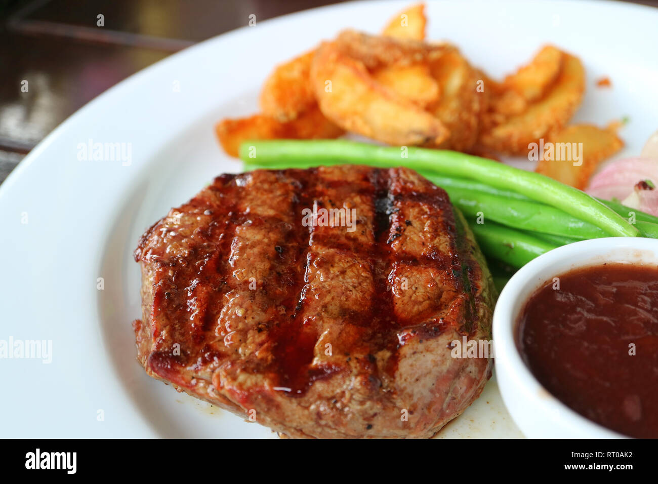 Geschlossen bis Gegrillte Filet Steak mit unscharfen gedünstetem Gemüse und Bratkartoffeln im Hintergrund Stockfoto