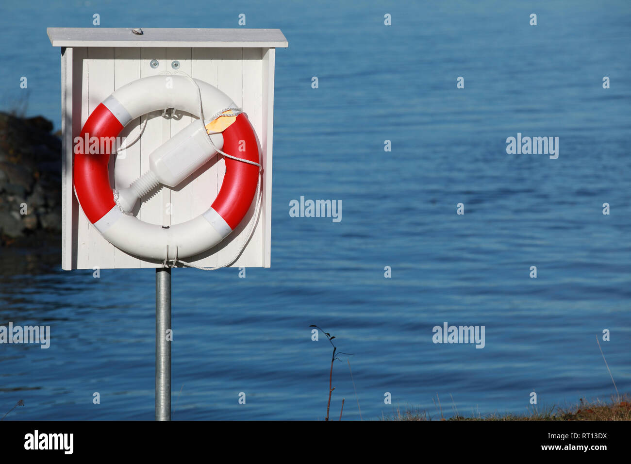 Rot weiss Rettungsring mit Seilen hängend im Holzkasten auf einem See Küste Stockfoto