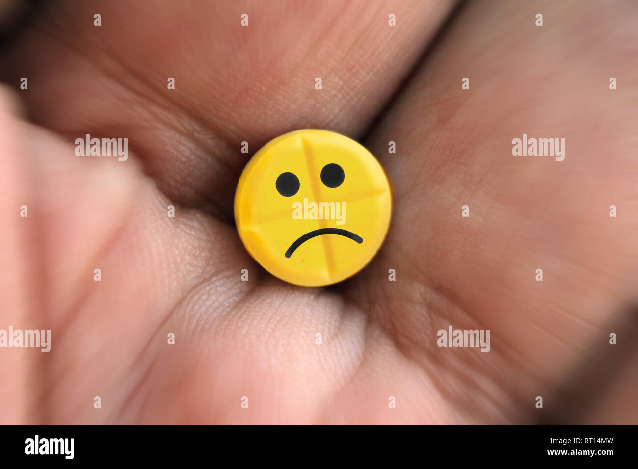 Pille mit traurige Smiley emoji Logo in der Hand, Nahaufnahme Stockfoto