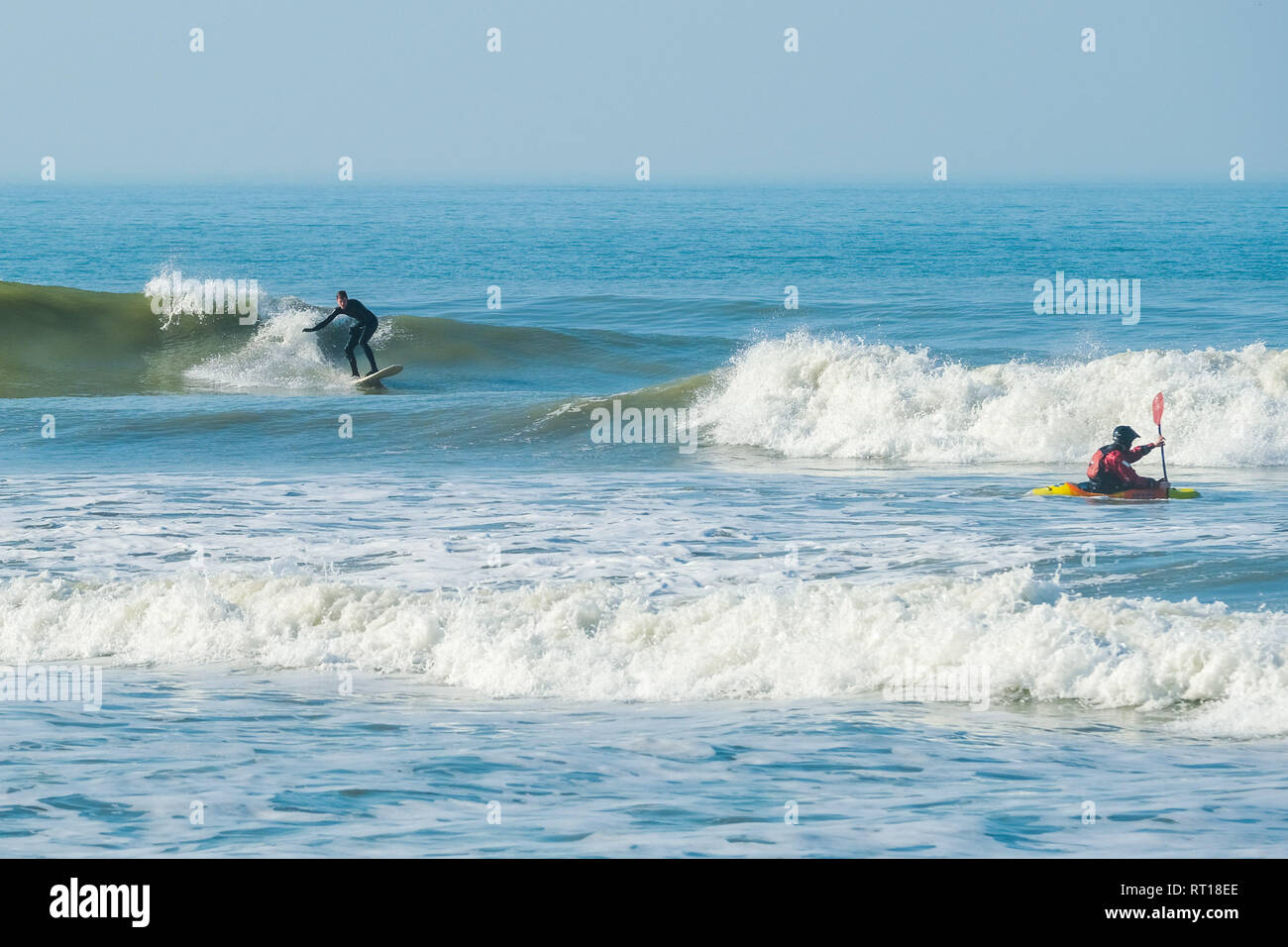 Aberystwyth Wales UK Mittwoch, den 27. Februar 2019. UK Wetter: Surfer und Kajakfahrer fangen die Wellen aus der Strand in Aberystwyth am Morgen, der die meisten der sensationell heiß und sonnig, 'Winter' Wetter, während es dauert. Das Wetter Prognose zu starten ab morgen zu verschlechtern, mit mehr typische windig und kühler Anfang März Foto erwartet: Keith Morris/Alamy leben Nachrichten Stockfoto