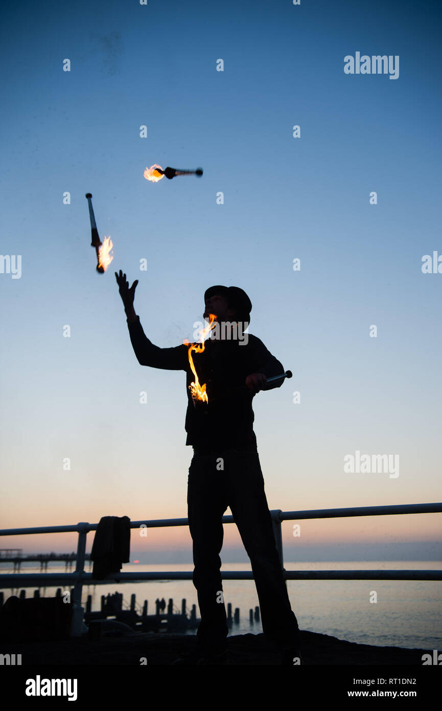 Aberystwyth Wales UK Mittwoch, den 27. Februar 2019. UK Wetter: ein Mann Jonglieren mit Feuer an der Promenade Aberystwyth, wie die Sonne, die die meisten der sensationell heiß und sonnig, 'Winter' Wetter, während es dauert. Das Wetter Prognose zu starten ab morgen zu verschlechtern, mit mehr typische windig und kühler Anfang März Foto Keith Morris/Alamy Live Nachrichten erwartet Stockfoto